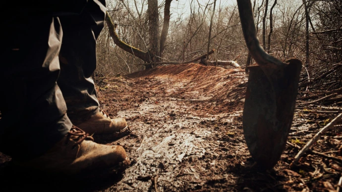 person in brown pants and brown boots holding brown wooden stick