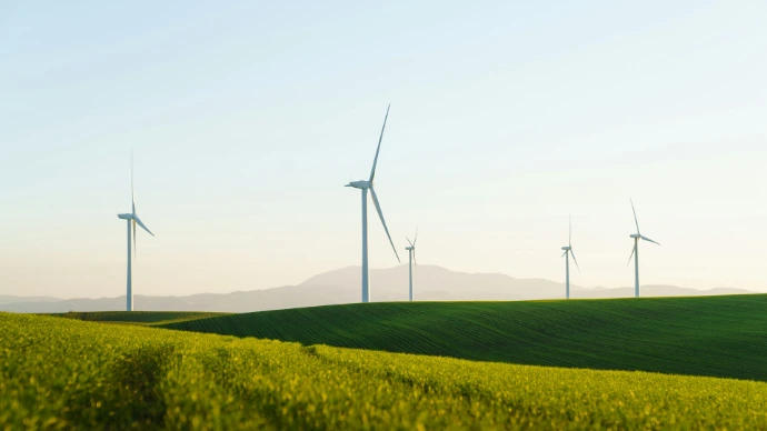 a field of green grass with wind turbines in the background