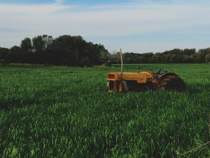 yellow farm tractor on green grassfield